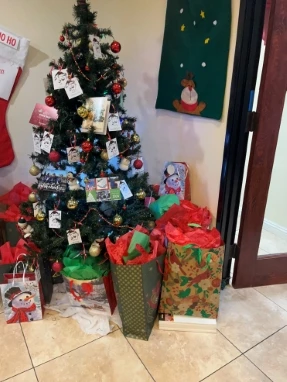 Close-up of a Christmas tree surrounded by holiday gift bags with festive decorations and stockings nearby.